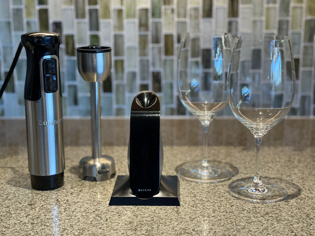 Image of the Aveine aerator, a disassembled immersion blender, and two wine glasses, sitting on a countertop.